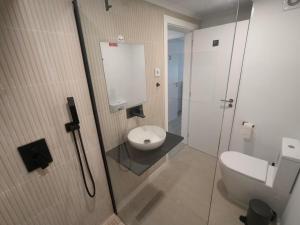 a bathroom with a toilet and a glass shower stall at Cubo Rooms Olhão in Olhão