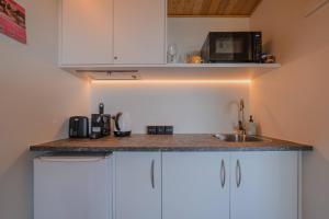 a kitchen with white cabinets and a sink and a microwave at Aurora Vista - Ohana in Lake Tekapo +26 photos