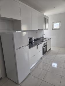 a white kitchen with white cabinets and a sink at Tina Bay in Mindelo