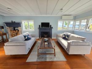 a living room with two couches and a coffee table at Kingfisher Lodge Waterfront Retreat in Tairua