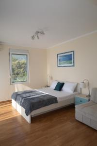 a white bedroom with a bed and a couch at Blue Horizon Villa DV in Dobra Voda +14 photos