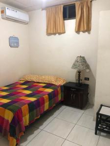 a small bedroom with a bed and a lamp at hospedaje Maluli suite girasol in Santa Elena