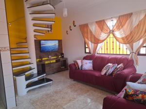 a living room with a red couch and a staircase at Recanto da praia in Bertioga