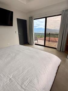 a bedroom with a large bed and a large window at Casa Colibrí in Alajuela
