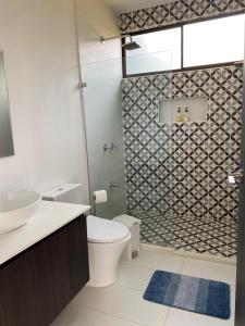 a bathroom with a toilet and a glass shower at Casa Colibrí in Alajuela