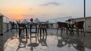 a table and chairs on a balcony with the sunset at Anubis Pyramids View Inn in Cairo