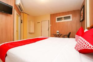 a bedroom with a large white bed with red pillows at Super OYO Naomi Heritage in Surabaya