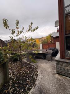 a patio with a bench and a table and a tree at Cardrona Alpine Luxe in Cardrona