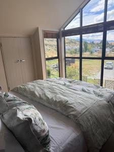 a bedroom with a bed and a large window at Cardrona Alpine Luxe in Cardrona