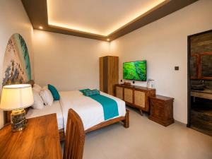 a bedroom with a bed and a table and a television at Cahya Pandawa Villa in Nusa Dua