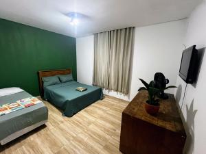 a bedroom with a bed and a tv and a table at My House Muriqui in Mangaratiba +31 photos