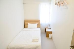 ein kleines weißes Zimmer mit einem Bett und einem Fenster in der Unterkunft EdoHouse -エドゥハウス- in Hida