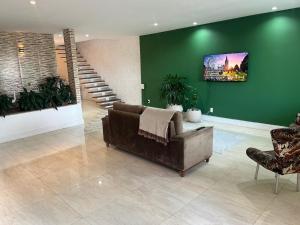 a living room with a couch and a green wall at My House Muriqui in Mangaratiba