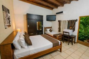 a bedroom with a bed and a desk and a television at Hotel El Maltese - Lakefront in Granada