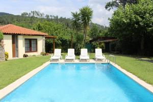 a swimming pool with two lawn chairs and a group at Leiras da Cachada - Gerês in Valdosende