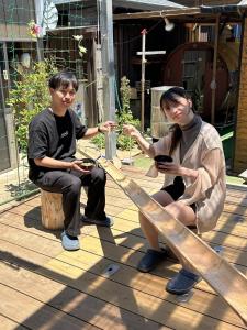 a man and a woman sitting on a wooden bench at ログハウス1棟貸し,持込み自由,サウナ,露天風呂にバーべキュウや薪割り,ソーメン流しに収穫体験が楽しめます in Kashima