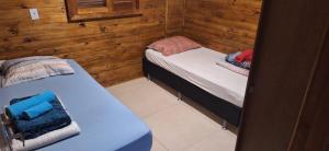 two twin beds in a room with wooden walls at Casa de Temporada BR 470 in Cafundó