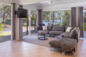 a living room with a couch and a tv at Amaroo Cottage Smiths Lake in Smiths Lake