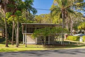a house with palm trees in front of it at Amaroo Cottage Smiths Lake in Smiths Lake