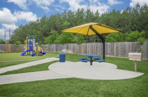 a park with a yellow umbrella and a playground at Humble cozy home in Humble