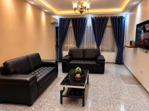 a living room with two leather couches and a table at Résidence Tango - Appartements Meublés - 4 types in Bafoussam