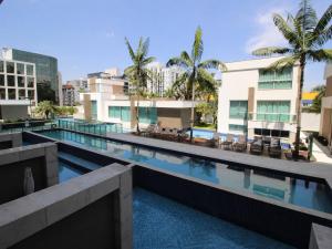 a large swimming pool with chairs and buildings at Apartamento Jade Hotel - Park Sul in Brasília