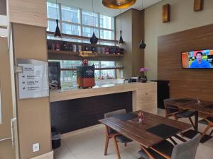 a restaurant with tables and a bar with a tv at Apartamento Jade Hotel - Park Sul in Brasília
