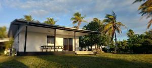a small white house with a table and some palm trees at Heaiti Lodge in Avatoru