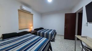 a room with two beds and a desk and a window at JESAVI Leones in Monterrey