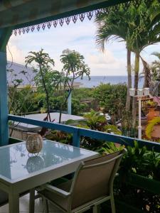 a table and chairs on a balcony with the ocean at Les Gîtes Blue Karaib in Sainte-Anne
