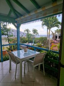a table and chairs on a balcony with a view of the ocean at Les Gîtes Blue Karaib in Sainte-Anne