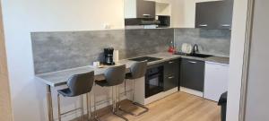 a kitchen with a counter and four chairs in it at Paradies Caraïbes II in Les Abymes