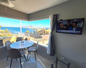 a living room with a table and a tv on the wall at Turquesa by the Sea, Elevated Ocean View Retreat in San Carlos