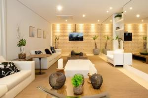 a living room with white furniture and a brick wall at Spazio Lume Luzes da Mooca in São Paulo