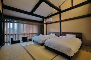 a bedroom with two beds and a large window at Obama Machiya Stay in Obama