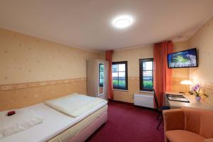 a bedroom with a bed and a desk and windows at Hotel Am Rathaus in Menden