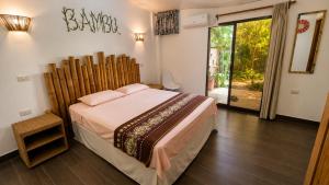 a bedroom with a bed with a wooden head board at Casita Madame - Frente al Mar con Desayuno Gourmet in Puerto López