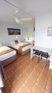 a bedroom with two beds and a table and chairs at Sunburst Motel in Gold Coast +28 photos