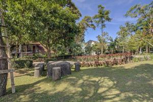 a park with trees and logs in the grass at Hotel O Villa Inn App Trawas Bintaro Syariah in Kemloko-gede