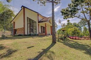 a house with a tree in front of it at Hotel O Villa Inn App Trawas Bintaro Syariah in Kemloko-gede