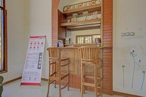 a kitchen with a bar with two stools and a mirror at Hotel O Villa Inn App Trawas Bintaro Syariah in Kemloko-gede +25 photos