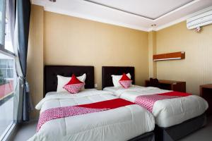 a bedroom with two beds with red and white pillows at Collection O 3431 Hotel Alpha Bandara in Palembang