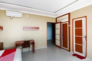 a bedroom with a desk and a bed and a table at Collection O 3431 Hotel Alpha Bandara in Palembang