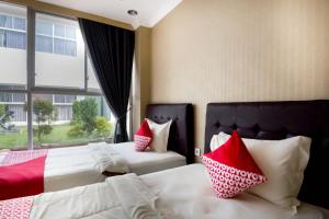 a bedroom with two beds with red and white pillows at Collection O 3431 Hotel Alpha Bandara in Palembang
