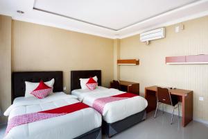 a hotel room with two beds and a desk at Collection O 3431 Hotel Alpha Bandara in Palembang