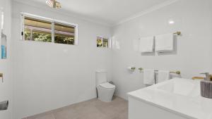 a white bathroom with a toilet and a sink at Honeybee House Cottage in the Rainforest in Kuranda +13 photos