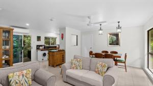 a living room with two couches and a table at Honeybee House Cottage in the Rainforest in Kuranda