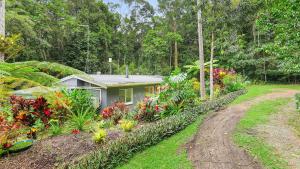 a house with a bunch of flowers in the yard at Honeybee House Cottage in the Rainforest in Kuranda