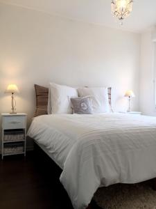 a bedroom with a white bed with pillows and a chandelier at Appartement Copenhague Disneyland in Montévrain