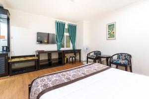 a bedroom with a bed and a desk and chairs at Royal Dalat Hotel in Da Lat
